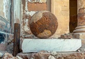 Ancient stone sphere rests on marble slab in ruins photo