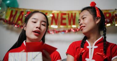Cheerful asian woman is holding a red envelope and chatting happily with her mother in the cozy living room. Asian family celebration Lunar New Year together photo
