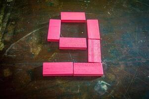 Red wooden blocks arranged in the shape of the number nine on a rustic wooden surface. Perfect for educational, numerical, or creative concepts photo
