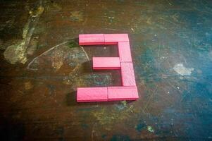 Red wooden blocks arranged in the shape of the number three on a rustic wooden surface. Perfect for educational, numerical, or creative concepts photo