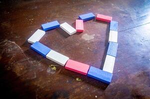 Colorful wooden blocks arranged in a heart shape on a rustic wooden surface, symbolizing love and creativity photo