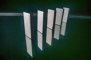 A row of five standing dominoes with their reflections on a glossy surface, creating a symmetrical and visually appealing pattern photo