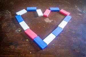 Colorful wooden blocks arranged in a heart shape on a rustic wooden table, creating a charming and playful design photo