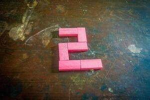 Red wooden blocks arranged in the shape of the number two on a rustic wooden surface. Perfect for educational, numerical, or creative concepts photo