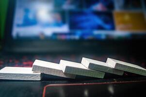 Close up of white wooden blocks falling in a domino effect on a laptop keyboard, symbolizing a chain reaction or cause and effect concept photo