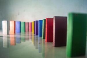 Colorful wooden blocks arranged in a row, creating a visually appealing pattern. The blocks are standing upright on a reflective surface, showcasing various vibrant colors photo