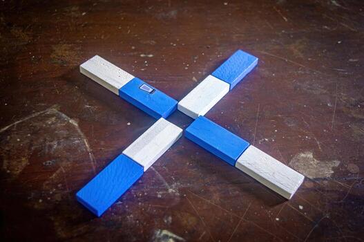 Wooden puzzle pieces arranged in an X shape on a rustic wooden surface. The pieces are painted blue and white, creating a visually appealing contrast photo