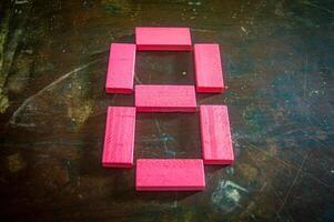 Red wooden blocks arranged in the shape of the number eight on a rustic wooden surface. Perfect for educational, numerical, or creative concepts photo