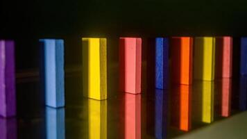 Colorful wooden blocks standing in a row on a reflective surface, creating a vibrant and visually appealing pattern photo