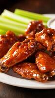 Hot and spicy chicken wings with celery and sauce on a plate photo