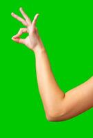 Hand making a gesture with green background in bright lighting during daylight hours photo