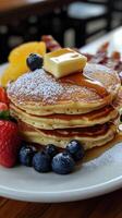Pancakes with fresh berries and honey on a white plate. photo