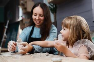 A mother and daughter enjoy clay modeling together in a cozy studio photo