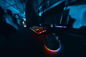 Computer setup featuring a colorful keyboard and mouse in a dimly lit room photo