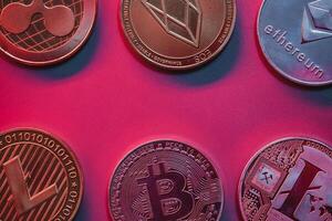 Stack of crypto coins on red, pink background with neon illumination. photo