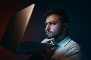 A man looks thoughtfully at the laptop screen. photo