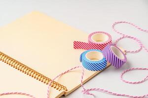 Colorful decorative tape and a spiral notebook ready for creative projects on a neutral background photo
