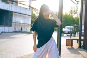 Stylish woman posing in urban setting at sunset wearing casual outfit and enjoying the warm evening light photo