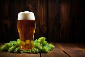Glass of beer with hops on wooden table and dark background photo