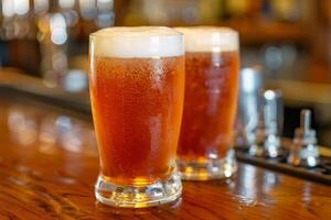 Two glasses of cold beer resting on a bar top photo