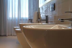 Modern bathroom sink and faucet with bidet in background photo