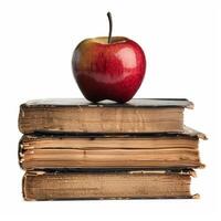 Red apple resting on stack of old books symbolizing knowledge and learning photo
