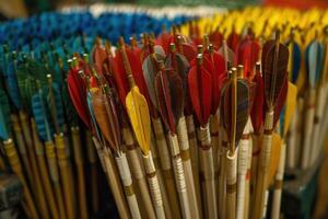 Colorful handmade arrows with natural feathers are standing in a box in a workshop photo