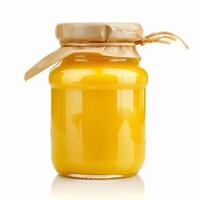 Glass jar of mango or peach puree covered with brown paper and tied with string on white background photo