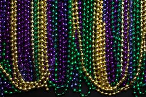 Colorful mardi gras beads hanging in vertical rows creating festive background photo