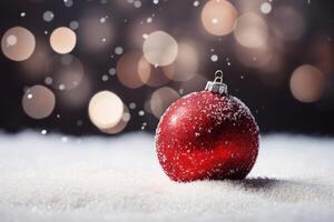 Red christmas ball resting on snow with soft lights and falling snowflakes in the background photo