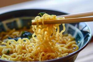 Chopsticks lifting noodles from bowl of ramen soup photo