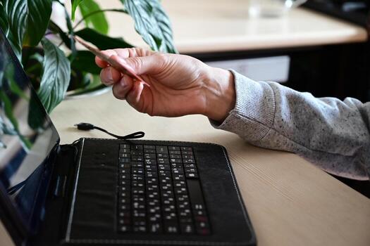 A black keyboard sits next to a credit card on a desk, with a hand preparing to pick it up. This suggests an e-commerce or financial transaction is about to take place photo