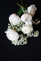 Fresh white peonies on a black, dark background. A condolence card. Wedding date. An invitation to a holiday. Congratulation.An empty space for text. View from above. He was lying flat. photo
