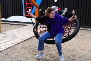 A girl swings on a round swing on the playground On a beautiful day photo