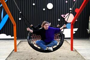 A girl swings on a round swing on the playground on a shunny day whith lought photo