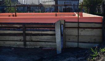 Wooden formwork on a sunny day with metal reinforcement prepared for pouring concrete. Installation using wire. Building a new house. photo