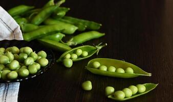 Green shoots of young peas On a beautiful day flowers and pods on a dark wooden background. selective focusing photo