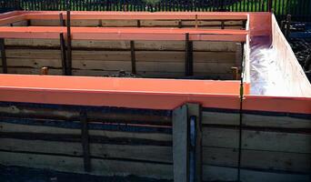 Wooden formwork with metal reinforcement prepared for pouring concrete. on a beautiful sunny morning photo