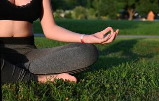 A girl on a wonderful day in a white sports uniform does yoga with a belt in nature on a sunny summer day. A yogi conducts a yoga class in the fresh air. photo