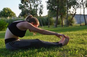 A girl in a white sports uniform does yoga on a beautiful sunny morning photo