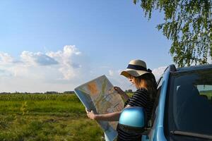 Rear view shot of couple driving on country road. Woman holding map and showing the route map to her boyfriend driving the car. Couple on a road trip. photo