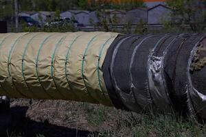a dilapidated old torn layer of insulation on the pipeline poorly insulates communications and requires repair photo