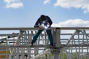 man welds at the factory on a wonderful day photo
