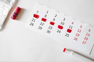 Women's menstruation Calendar, sanitary napkin in a package with pink alarm clock on a pink background. The concept of critical days time photo