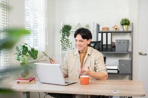 A confident Asian businessman having an online meeting with his client through his laptop. photo