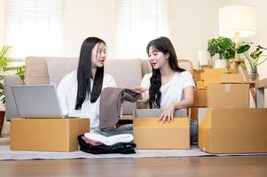 Two Asian female online shop owners are working in the living room, discussing while packing goodies photo