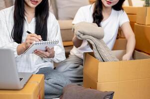 A close-up of two women checking orders and packing goodies into cardboard boxes. photo