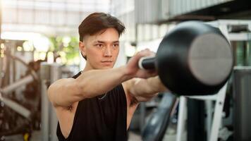 A determined and strong Asian man is working out with a kettlebell, exercising in the gym. photo