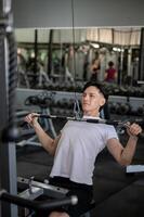 A strong and determined Asian man is working out with a cable machine to train his chest muscles. photo