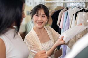A customer is friendly asking for advice from a shop employee while selecting a dress to buy. photo